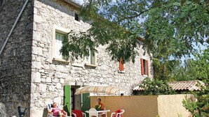 A stone building with a balcony, outdoor seating, and a tree providing shade. - 1 bedroom nice apartment in La Beaume (La Beaume)