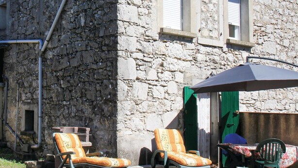 A stone building with two lounge chairs and a table under a large umbrella. - 1 bedroom nice apartment in La Beaume (La Beaume)