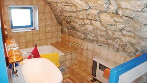 A bathroom with a stone wall, a window, a bathtub, a sink, and a shower area. - 1 bedroom nice apartment in La Beaume (La Beaume)