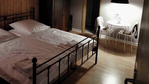 Une chambre à coucher comprenant un lit, une armoire, un bureau avec une chaise et un luminaire suspendu.