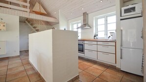 A spacious kitchen with a central island, a built-in oven, and a microwave. There is a staircase leading to an upper level.