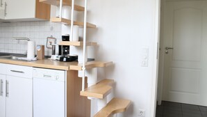 Eine Küche mit weißen Schränken, einer Holzauskleidung und einer weißen Wendeltreppe.