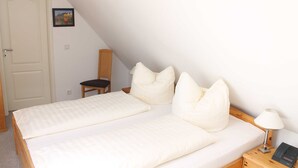 Ein Schlafzimmer mit zwei Betten, einem Sessel, einem Nachttisch mit Lampe und einer Tür.