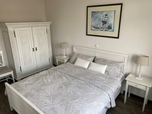 A bedroom with a large bed, two bedside tables, a wardrobe, and a framed picture on the wall. - (26) 2-room apartment Ostseeallee - apartment house dune castle (Kühlungsborn)