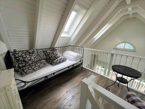 A loft bedroom with a bed, a small table, and a balcony with a railing. - (26) 2-room apartment Ostseeallee - apartment house dune castle (Kühlungsborn)
