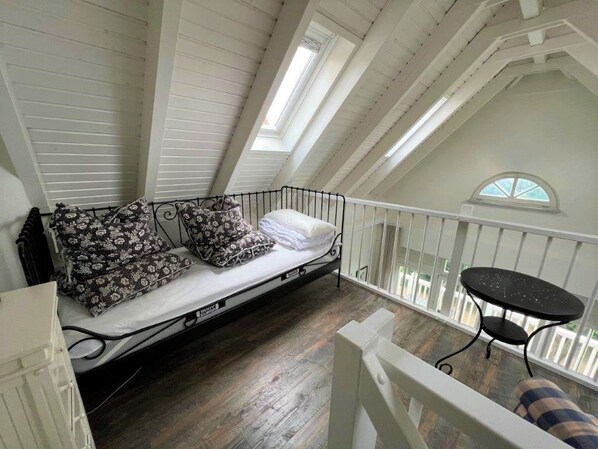 A loft bedroom with a bed, a small table, and a balcony with a railing. - (26) 2-room apartment Ostseeallee - apartment house dune castle (Kühlungsborn)