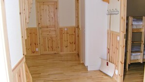 Habitació amb revestiment de fusta, una porta blanca, una paret blanca i un llit superposat amb matalàs.