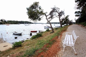 A bench by a lakeside path with boats in the water. - Holiday apartment 100 m from the beach (Banjole)