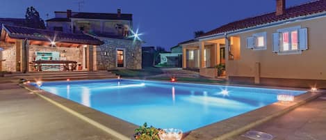 Una piscina con cubierta de piedra, una zona de bar y un edificio de piedra al fondo.