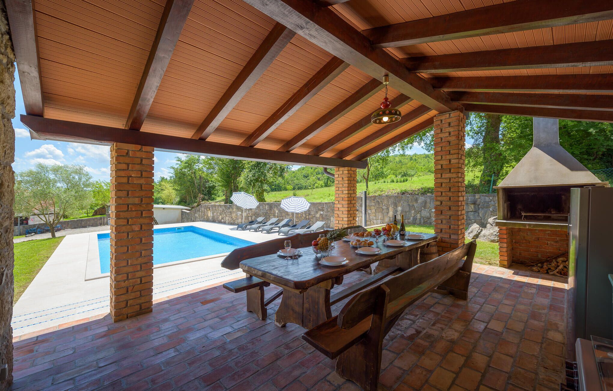 An outdoor patio with a pool, a barbecue grill, and a dining table set for four.
