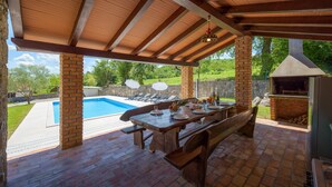 Un patio exterior con piscina, una parrilla y una mesa de comedor para cuatro.