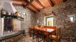 Un comedor rústico con pared de piedra, vigas de madera y chimenea de ladrillo.