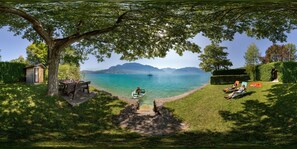 Blick auf einen See mit Essbereich, einem Boot und einer Person, die sich sonnt.