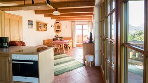 Una cocina con horno Bosch, una zona de comedor con mesa y sillas, y vistas amplias a través de grandes ventanales.