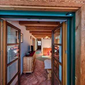 Ein Holzinnenraum mit Fliesenboden, einem Holzkabinett und einem Bett mit roter Decke.