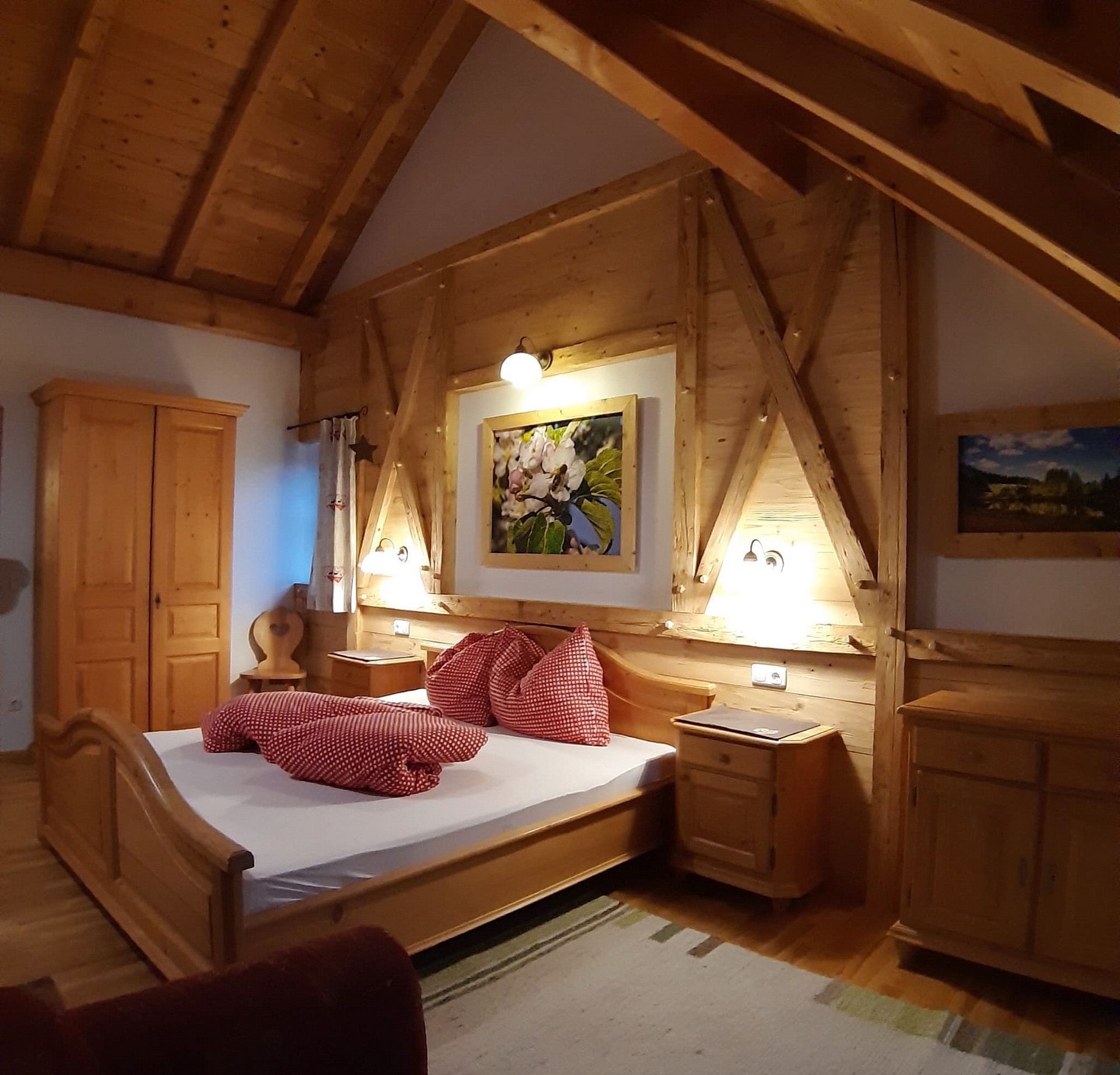 A wooden bedroom with a bed, a nightstand, a wardrobe, and a painting on the wall.