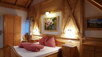 A wooden bedroom with a bed, a nightstand, a wardrobe, and a painting on the wall.