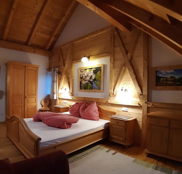 Un dormitorio de madera con una cama, una mesita de noche, un armario y un cuadro en la pared.