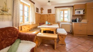 Acogedora habitación tipo cabaña con un banco de madera, una mesa, un sofá y una zona de cocina con microondas.