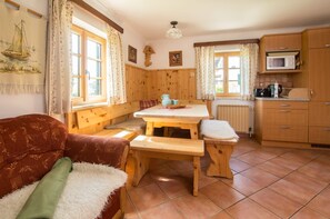 A cozy cabin-style room with a wooden bench, a table, a sofa, and a kitchen area with a microwave. - Apartment Mondsee - apartment on the farm "Margarethengut" am Attersee (Buchenort)