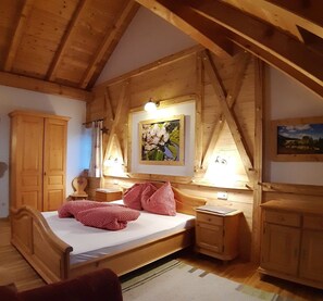 A wooden bedroom with a bed, a nightstand, a wardrobe, and a painting on the wall.