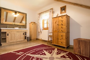 A rustic bathroom with wooden cabinets, a mirror, and a red patterned rug.