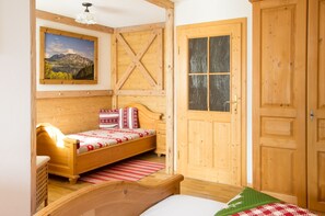 Una habitación de madera con una cama, un armario de madera y una puerta con ventanal.