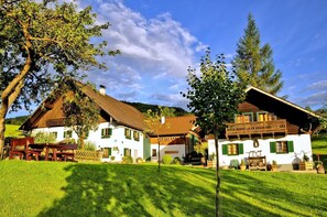 A traditional chalet-style building with a sloped roof, wooden shutters, and a well-maintained lawn. - Apartment Mondsee - apartment on the farm "Margarethengut" am Attersee (Buchenort)