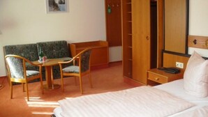 A hotel room with a bed, a sofa, a desk, and a wardrobe. - Studio - Hotel Reke (Hotel Admin) (Plau am See)