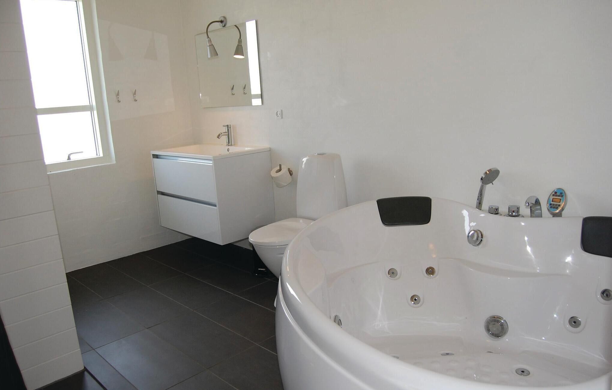 A modern bathroom with a white sink, toilet, and a large bathtub.