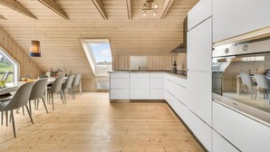 A modern kitchen with wooden beams, a skylight, and a dining area with chairs and a table. - Amazing home in Skjern with sauna (Skjern)