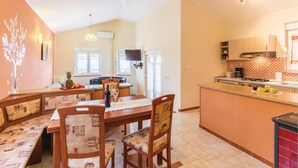 Una cocina amplia con comedor, que cuenta con una isla grande, muebles de madera y un salpicadero de azulejos.