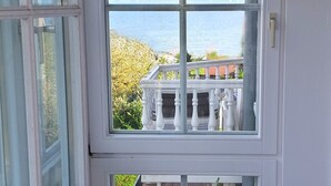 Een kamer met een groot raam dat uitzicht biedt op een balkon en de zee.