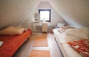 Cozy attic bedroom with two single beds, a desk, and a mirror.