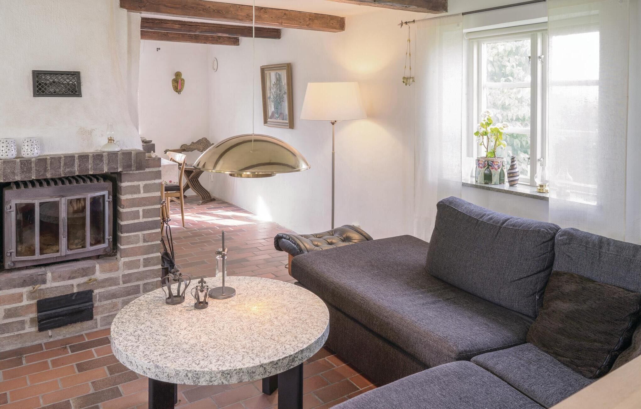 A cozy living room with a fireplace, a round table, a sofa, and a window with a view.