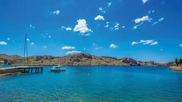 Un lac d’un bleu profond, avec des bateaux amarrés à un quai, le tout entouré de collines rocheuses.