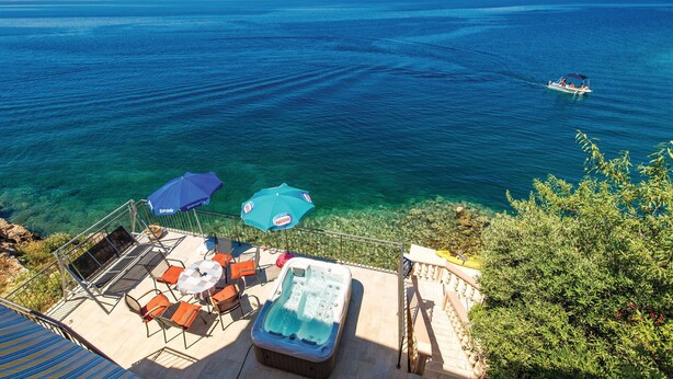 A balcony with outdoor seating, a hot tub, and clear views of the sea.
