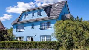 A two-story house with a sloped roof, multiple windows, and a balcony. - Apartment 1 - Apartments in Blu Hus (Kröslin)