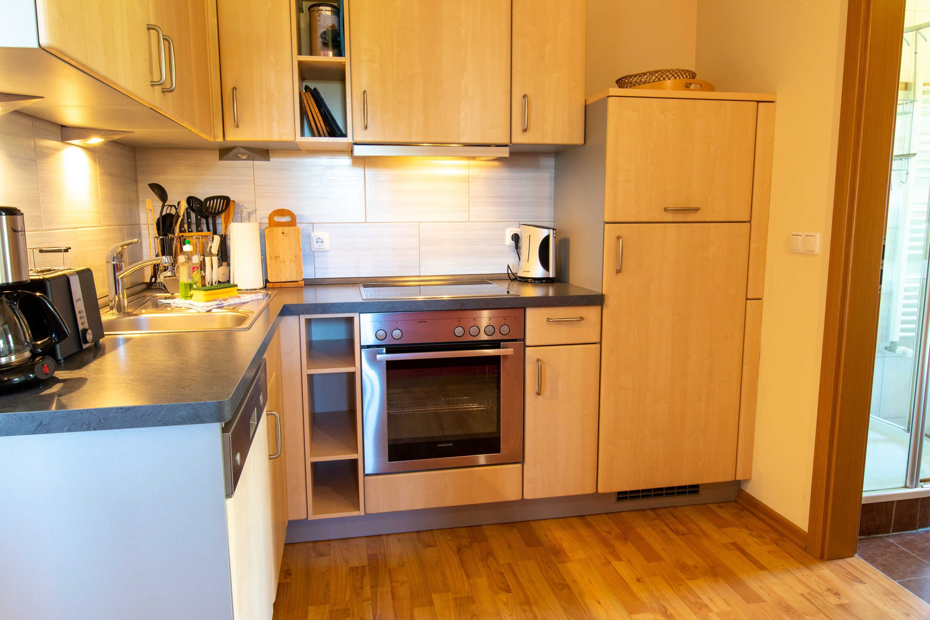 A modern kitchen with wooden cabinets, a built-in oven, and a stainless steel sink.