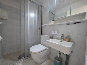 A bathroom with a toilet, sink, and shower area. - Vacation apartment Alfredo (Wustrow)