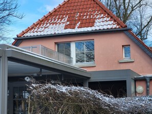 A house with a red-tiled roof, a balcony, and a garage. - Vacation apartment Alfredo (Wustrow)