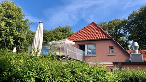 Una casa con techo de tejas rojas, una ventana y una chimenea.