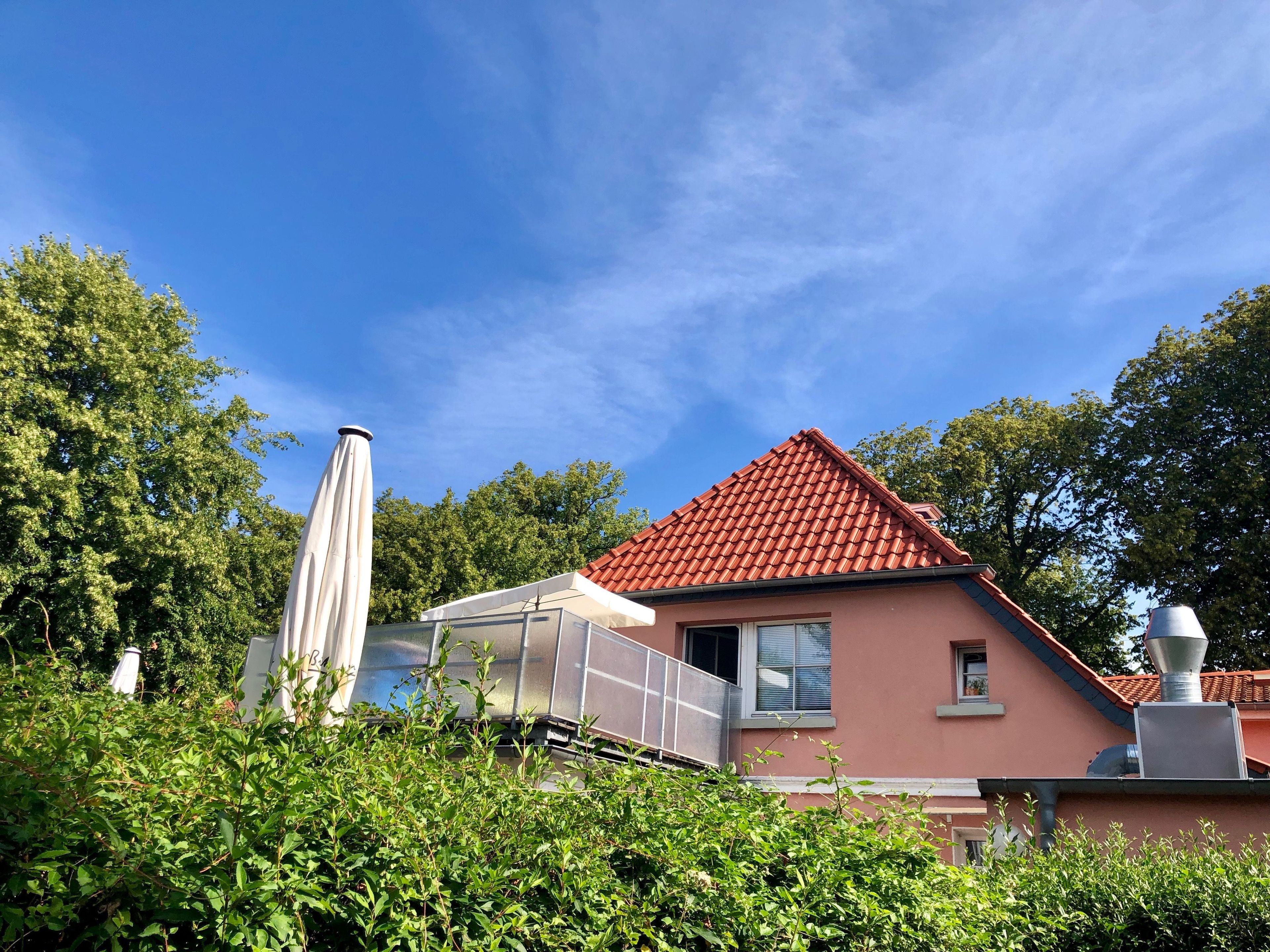 Une maison avec un toit recouvert de tuiles rouges, une fenêtre et une cheminée.