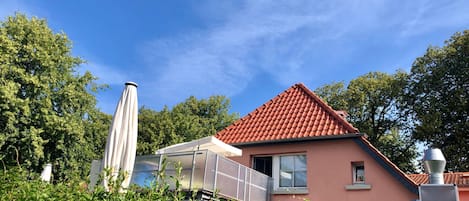 Una casa con techo de tejas rojas, una ventana y una chimenea.