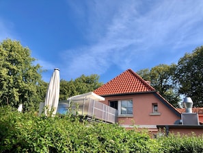 Une maison avec un toit recouvert de tuiles rouges, une fenêtre et une cheminée.