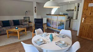 Una sala de estar moderna con comedor, un sofá, una mesa de centro y una cocina al fondo.