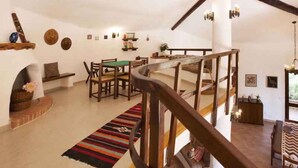 Ein rustikales Interieur mit einer Holztreppe, einem Essbereich mit einem grünen Tisch und einem farbenfrohen Teppich.