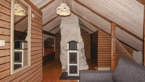 Una camera mansardata accogliente con pareti in legno, un divano grigio e una piccola finestra.