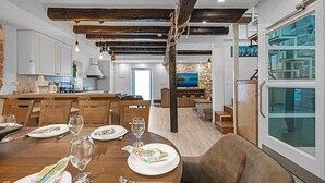 A dining area with a wooden table set for a meal, a stone wall, and a large window with a view. - Lovely home in Murter with WiFi (Murter)