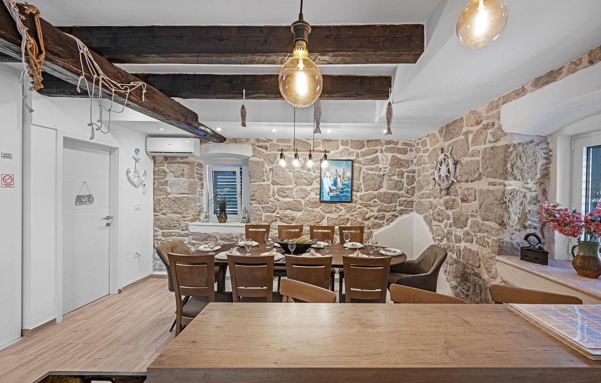 Un comedor rústico con mesa y sillas de madera, paredes de piedra y una lámpara colgante.